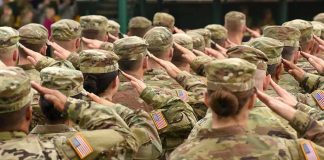 Soldiers in camouflage uniforms salute in formation