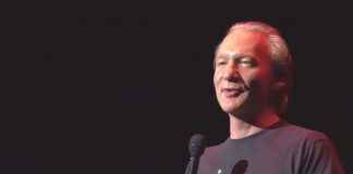 Maher Walk-Back On Trump STUNS Political Base comedian holding a microphone on stage