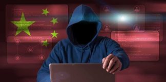 Hooded figure using a laptop with red cybersecurity graphics