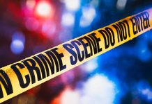 Fashion Power Couple Found SHOT DEAD yellow crime scene tape with blurred police lights