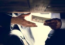 Hands exchanging cash under a table