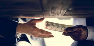 How City Halls Are WASTING Your Tax Dollars Hands exchanging cash under a table