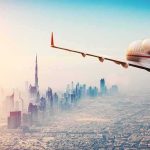 Private jet flying over a modern city skyline at sunrise
