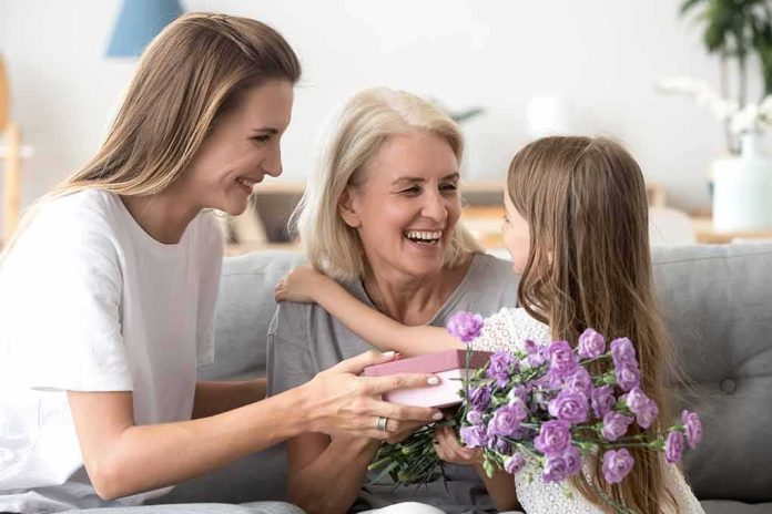 Brit Marling smiling with two others as a child gives flowers and a gift