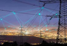 Power transmission towers over a city at dusk with connected network lines