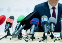 NFL Owner Tied to EPSTEIN Keeps His Team microphones clustered on a table at a press conference