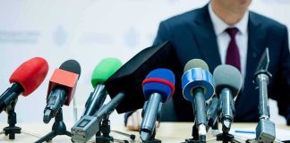 NFL Owner Tied to EPSTEIN Keeps His Team microphones clustered on a table at a press conference