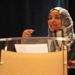 Ilhan Omar’s CITIZENSHIP Targeted by Feds Ilhan Omar speaking at a podium with a microphone