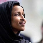 Ilhan Omar’s Lawyers Cry FOUL Over Raid Ilhan Omar in profile wearing a black headscarf outdoors