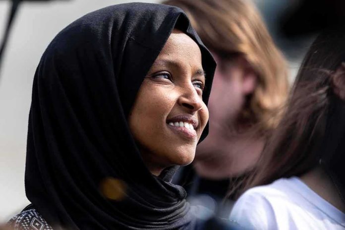 Ilhan Omar smiling in a black hijab at an outdoor event