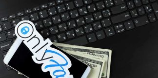 Smartphone with OnlyFans sticker and cash on a laptop keyboard