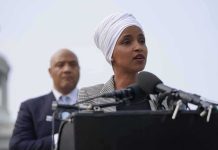 Trump Tells Ilhan Omar to RESIGN Ilhan Omar speaking at a podium with André Carson standing behind