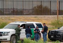 DHS Alert Warns Agents of ABDUCTION Plots law enforcement officers confer beside patrol vehicles near a border fence