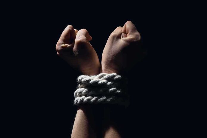 Hands bound with white rope against dark background