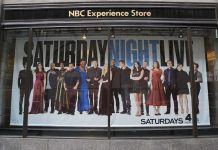 SNL Host Goes After Cancel Culture in WILD Monologue Storefront window with large SNL poster featuring Leslie Jones, Bobby Moynihan, Michael Che, Shirley Ellis, Kenan Thompson, and Richard Z. Kruspe